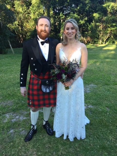 Couple outdoors, groom in traditional Scottish tartan kilt and bride in a lace gown