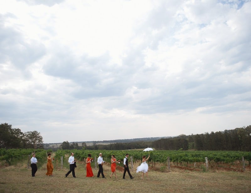 Bridal party of eight walking in a line between rows of vines at a vineyard wedding the Hunter Valley NSW