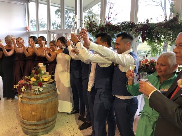 Bride, groom and bridal party raising champagne glasses in a toast at Otto House, Denham Court NSW