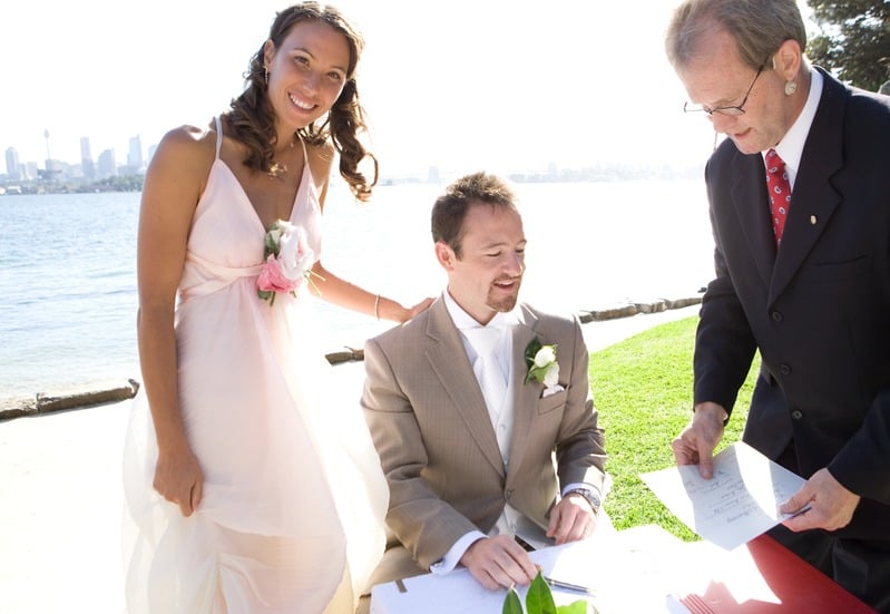 Bride and groom signing the marriage register at a harbour-side ceremony at Bradleys Head, NSW