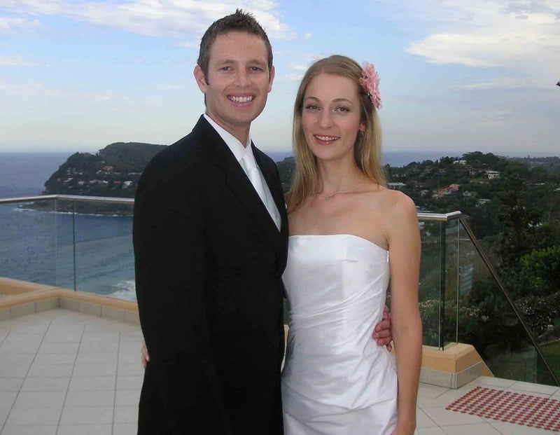 Bride and groom smiling together on a coastal balcony with ocean and cliffs behind at Jonah's Restaurant, Palm Beach NSW